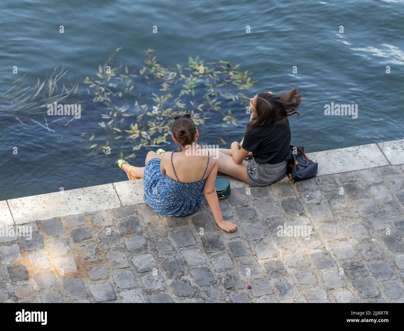 PARIGI / FRANCIA - 28 GIUGNO 2019: Due ragazze belle e giovani che si rilassano durante la calda giornata estiva sul fiume Senna a Parigi, Francia Foto Stock