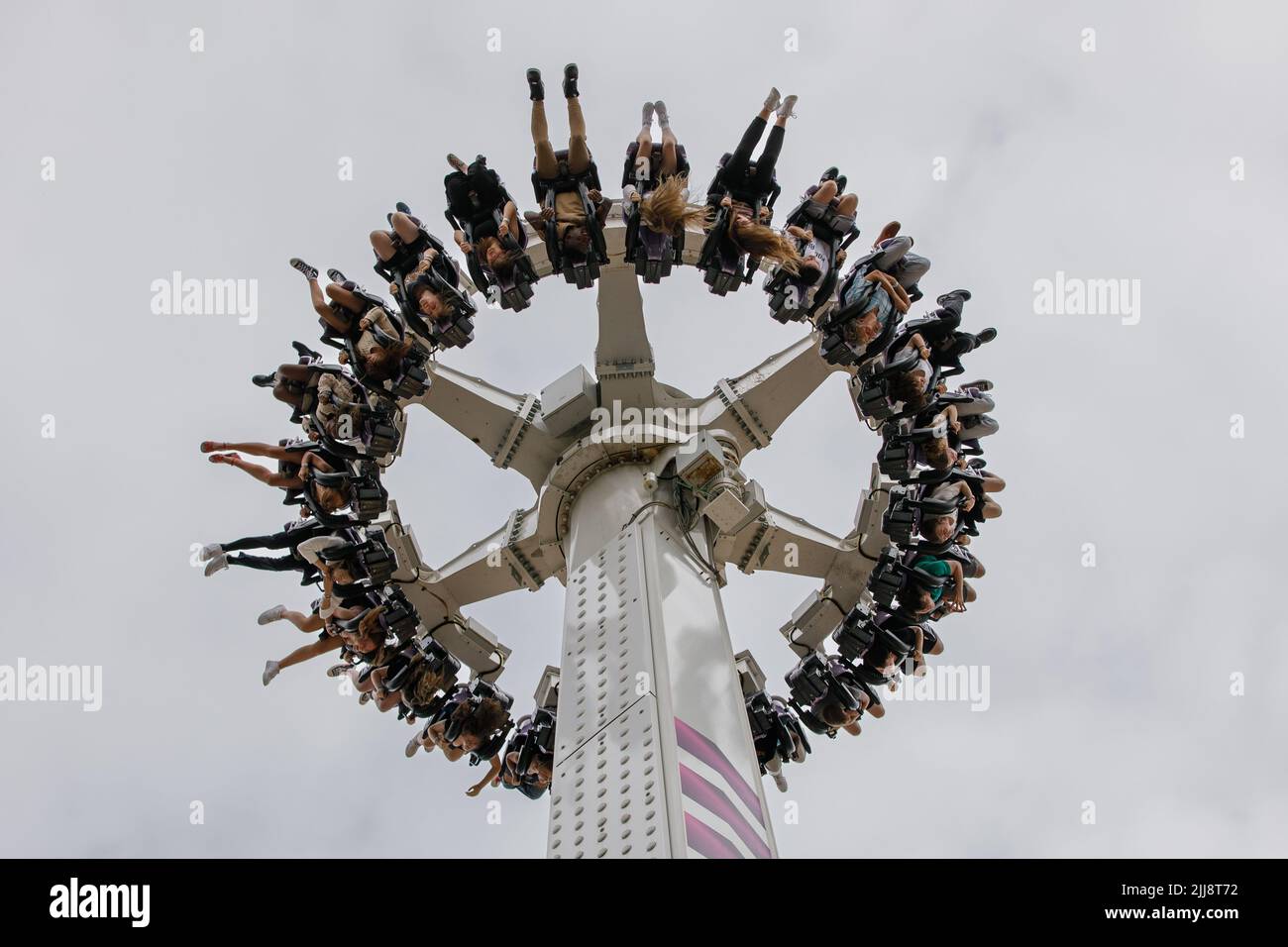 Un giro a pendolo in gondola a mezz'aria con persone che pendono a testa in giù con le gambe in aria. Foto Stock