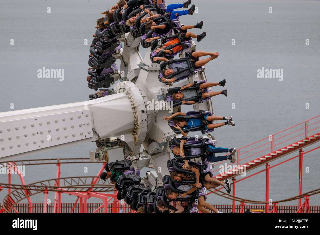 Un giro a pendolo in gondola a mezz'aria con persone che pendono a testa in giù con le gambe in aria. Foto Stock
