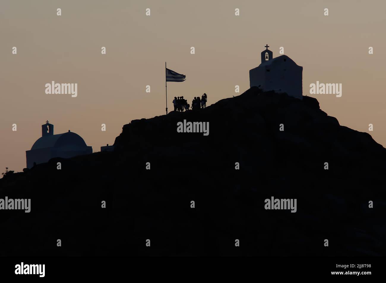 I turisti esplorano le pittoresche piccole cappelle sulla collina sulla splendida isola di iOS Grecia mentre il sole tramonta Foto Stock