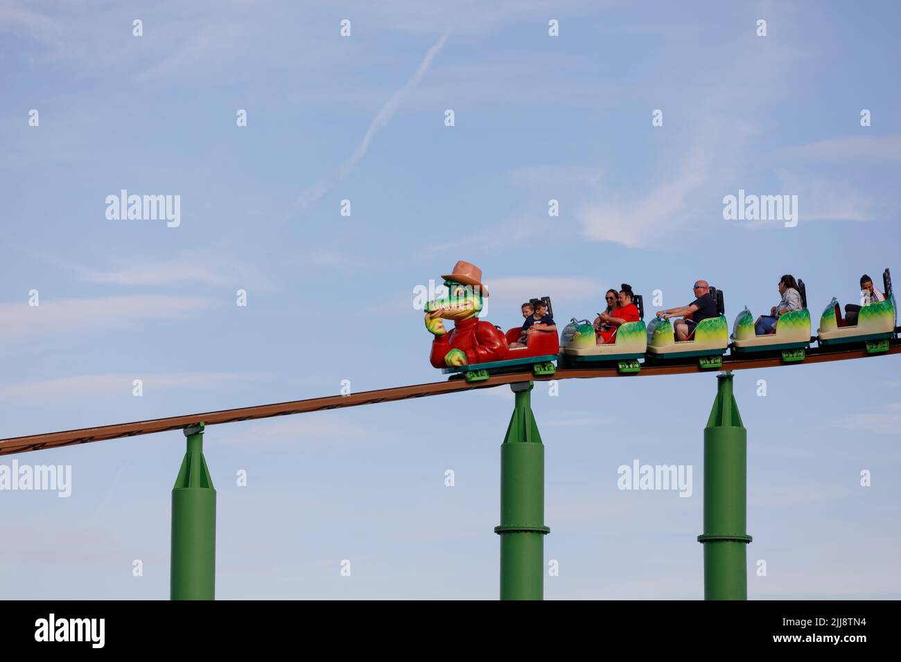 Bambini su una montagne russe con un cartoon a coccodrillo. Isolato su sfondo cielo chiaro. Green Scream, Adventure Island Foto Stock