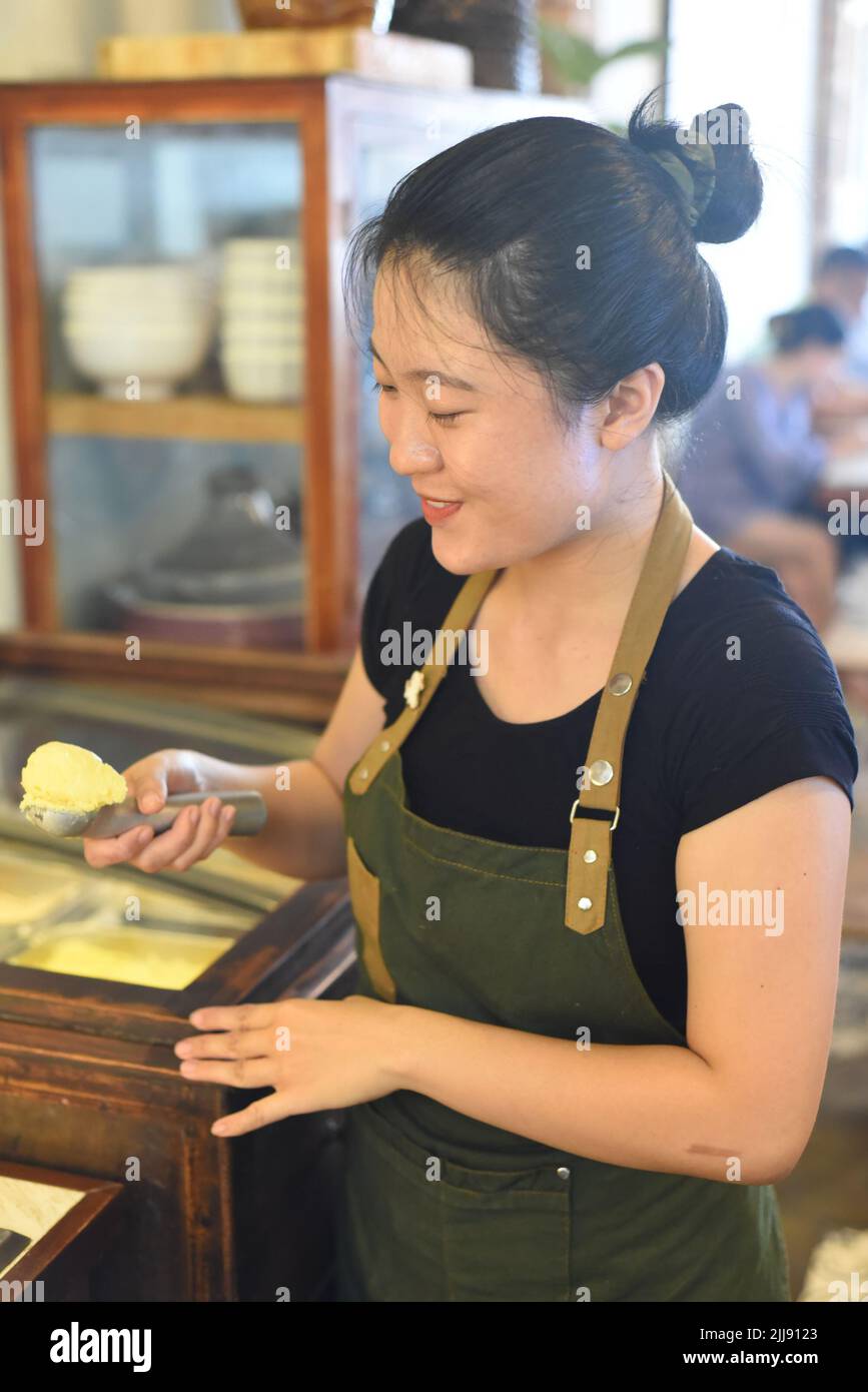 Cameriera vietnamita che mostra una paletta di gelato di mango fatto in casa in caffetteria Foto Stock
