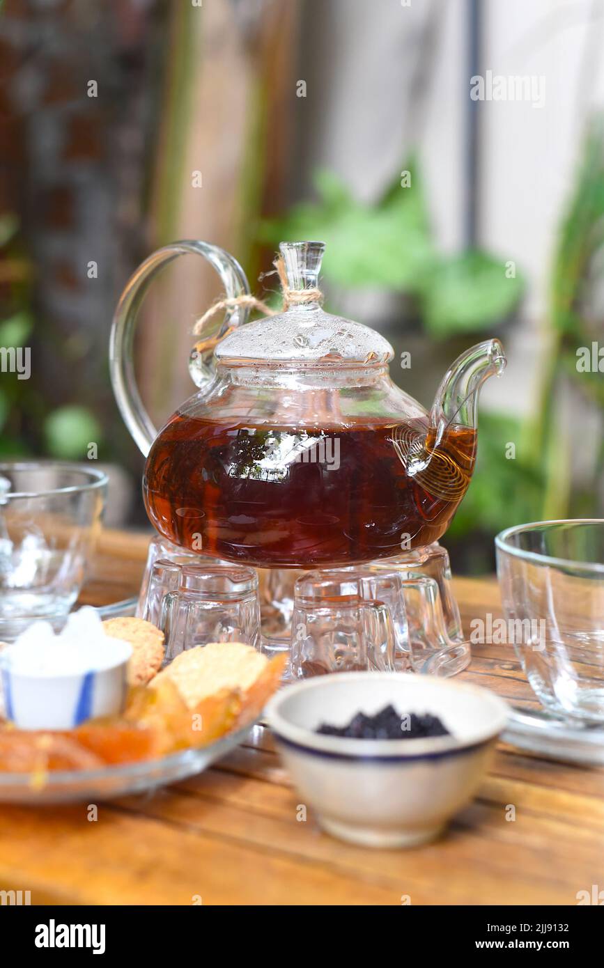 Tè Earl Grey in teiera di vetro con tazze e frutta cristallizzata su tavola di legno Foto Stock