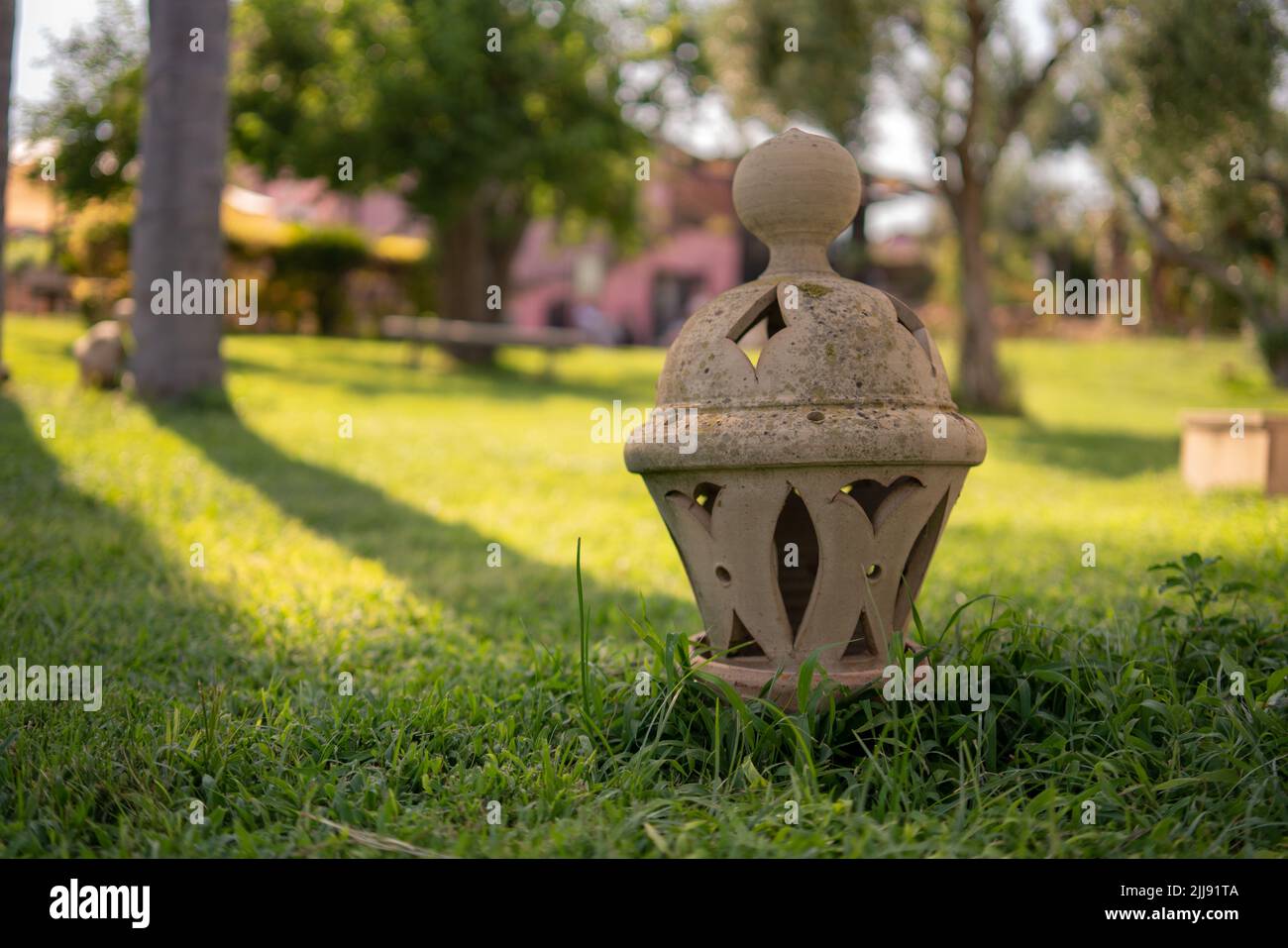 ceramica lanterna argilla ceramica seduta su erba in un giardino durante il tramonto sunrse Foto Stock