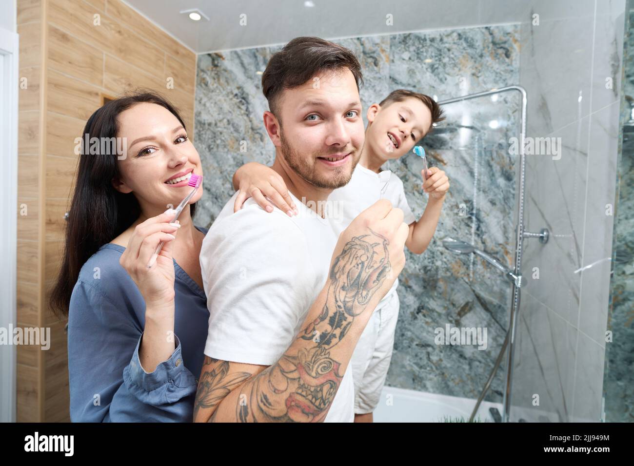 Mamma, papà e figlio si divertono a spazzolare i denti in bagno Foto Stock
