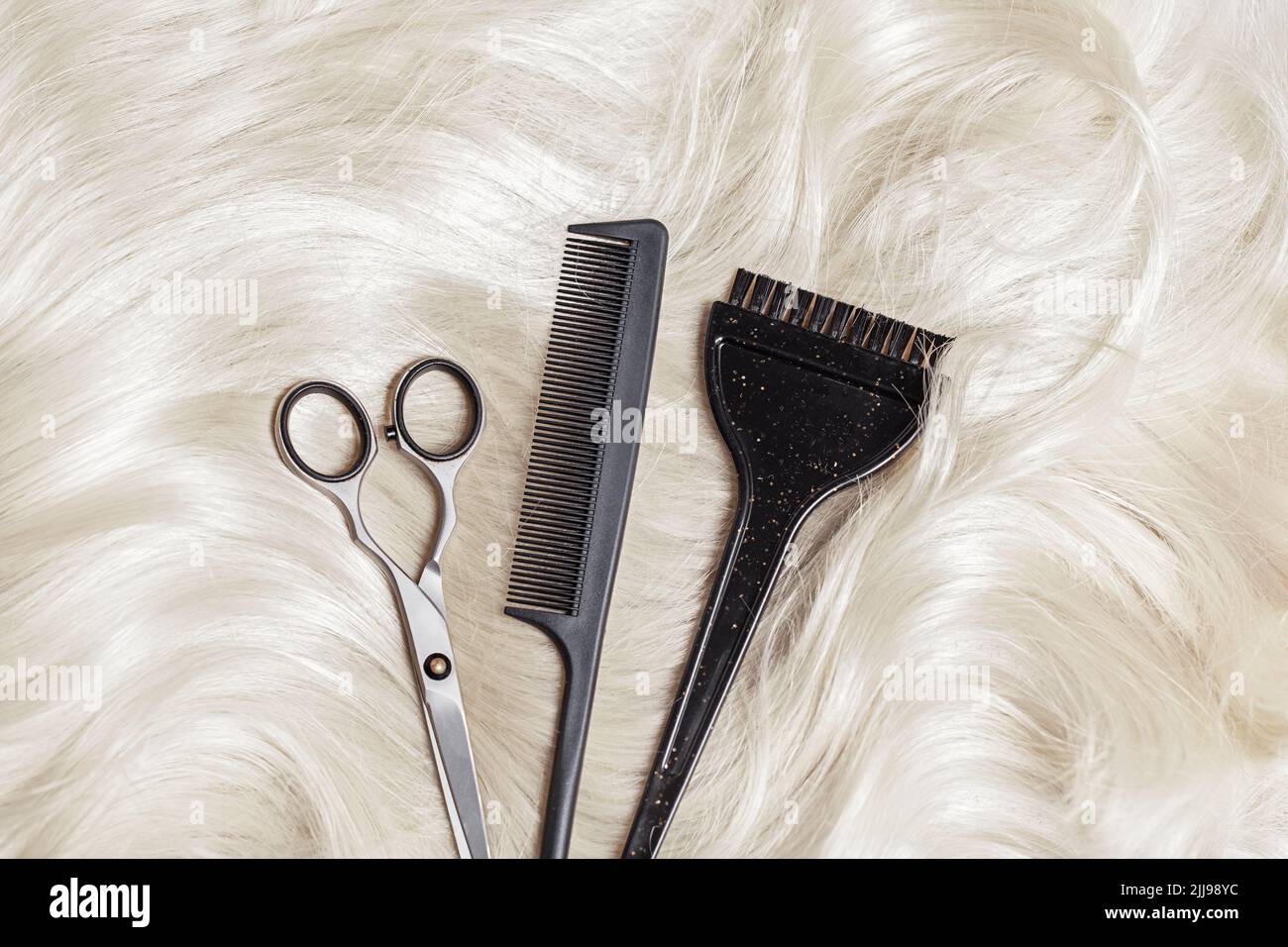 Forbici, pettine e spazzola sui capelli biondi. Background professionale di strumenti barbiere. Parrucchiere concetto di attrezzature per il salone Foto Stock