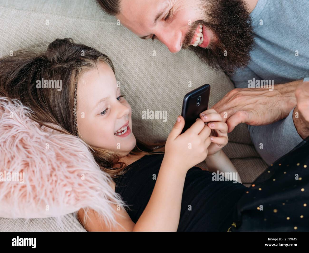 famiglia tempo libero ragazza papà guardare telefono gioia risate Foto Stock