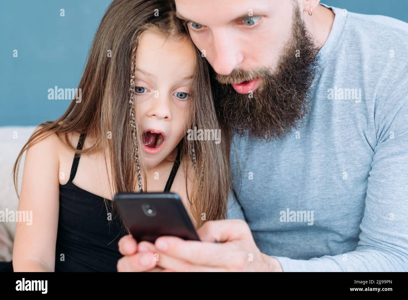 famiglia tempo libero shock stupito papà capretto reazione telefono Foto Stock