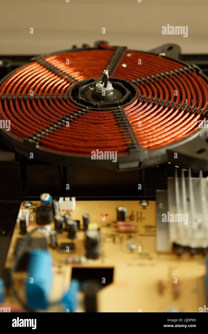 Spirale elettromagnetica di un fornello ad induzione. Parti per cucine a induzione. Elemento riscaldante per un fornello a induzione. Serpentina di riscaldamento di un cuoco a induzione Foto Stock