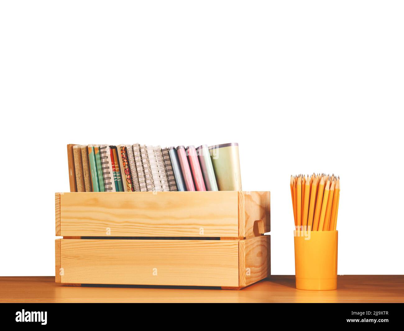 Quaderni di scuola in fila in una scatola di legno e matite su sfondo bianco. Concetto di istruzione - la scrivania nell'auditorium. Concetto di ritorno alla scuola Foto Stock