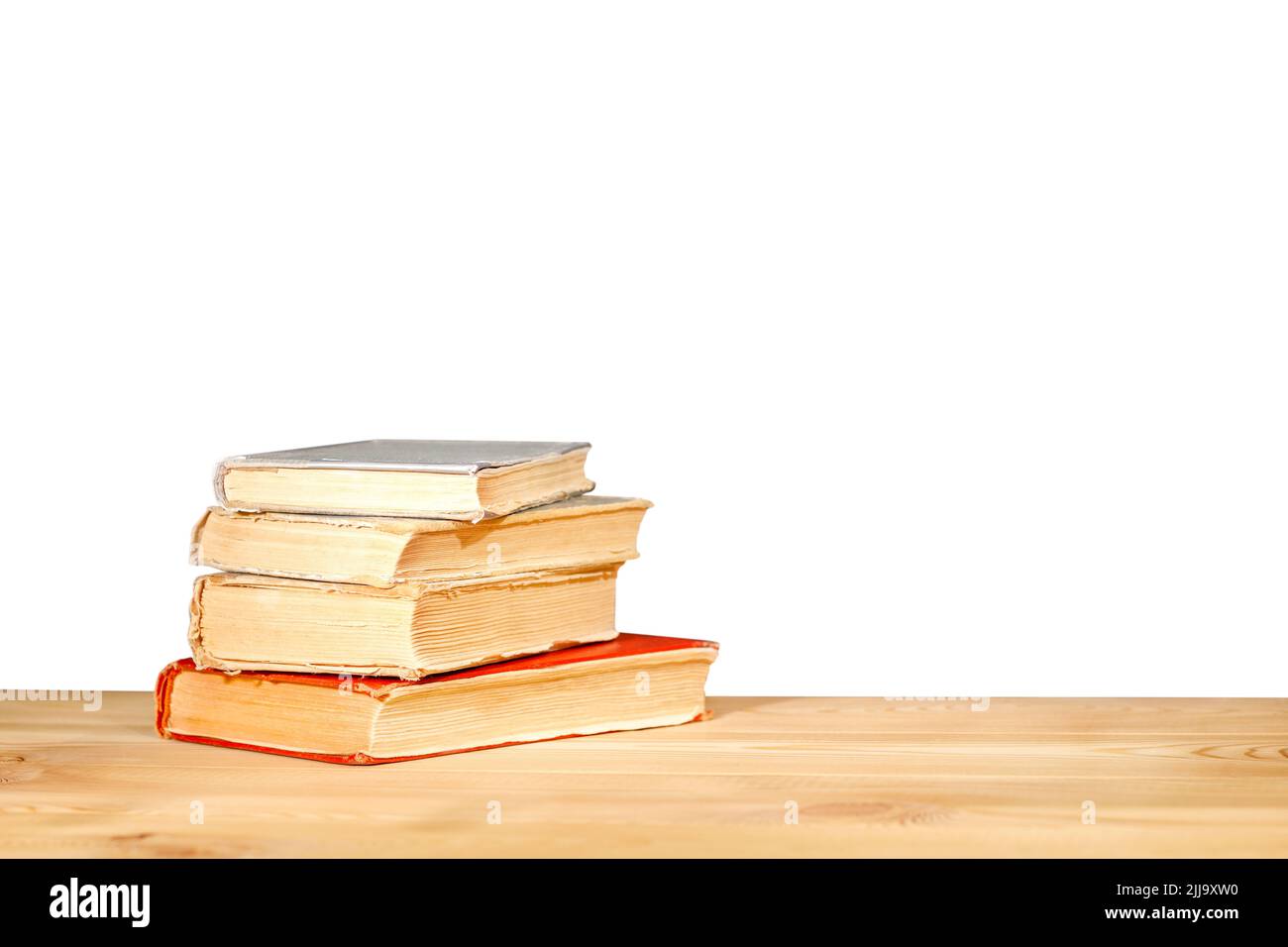 Vecchi libri di scuola che si trovano su un banco di legno di fronte su uno sfondo bianco. Concetto di istruzione - la scrivania nell'auditorium. Concetto di ritorno alla scuola Foto Stock