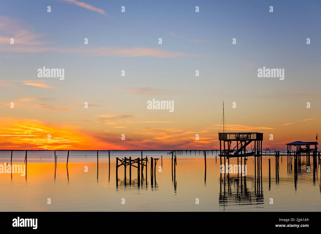 Il sole tramonta dietro le banchine e i moli di pesca su Coden Beach, 24 dicembre 2013, a Coden, Alabama. Foto Stock