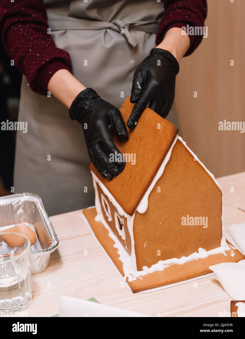 il processo di preparazione di una casa di pan di zenzero, incollando il tetto di zenzero con glassa, stringendo stretto Foto Stock