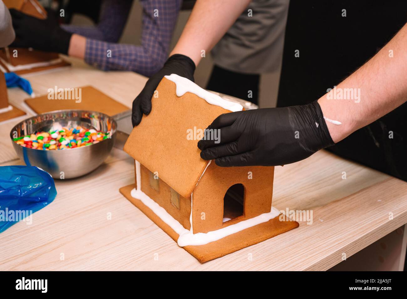 il processo di preparazione di una casa di pan di zenzero, incollando il tetto di zenzero con glassa, stringendo stretto Foto Stock