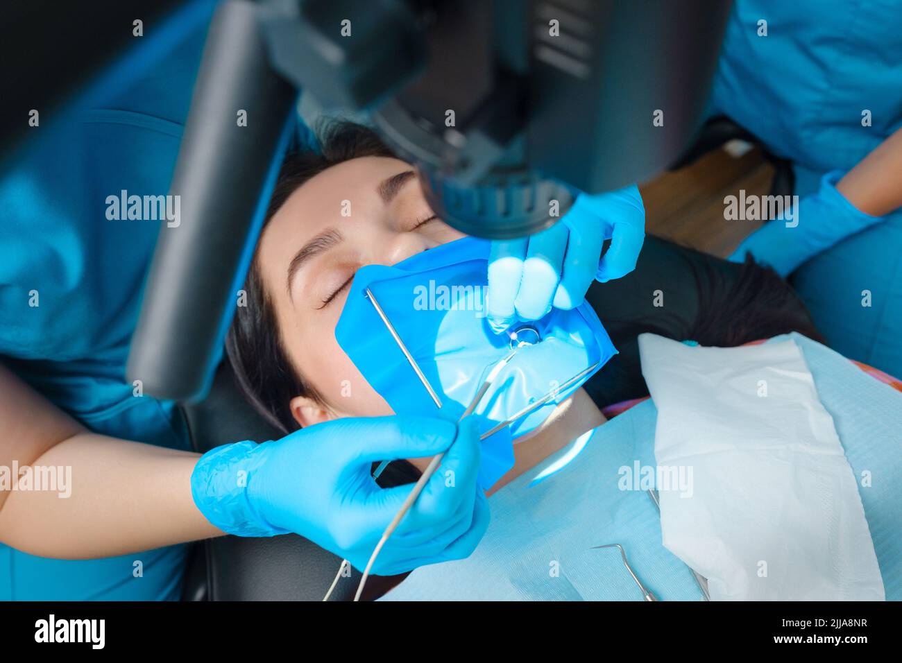 Trattamento fotoendodontico dei canali dentali nel molare inferiore del dente permanente con lima endodontica con localizzatore apicale, dente con morsetto attaccato Foto Stock