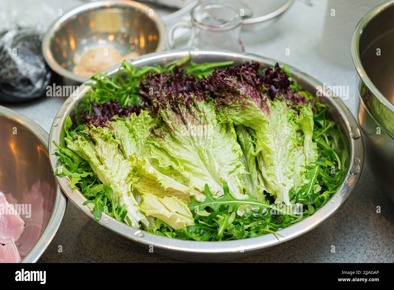 Una ciotola di foglie lavate di rucola e lilla rossa. Foglie di lattuga bagnate pronte per la cottura Foto Stock