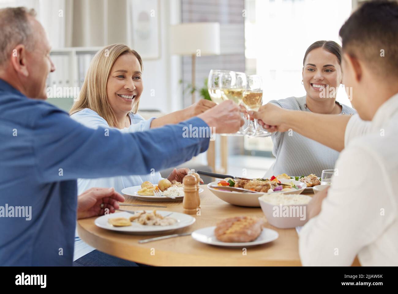 A molti, molti di più. Una famiglia tostatura con vino mentre si pranzano insieme a casa. Foto Stock