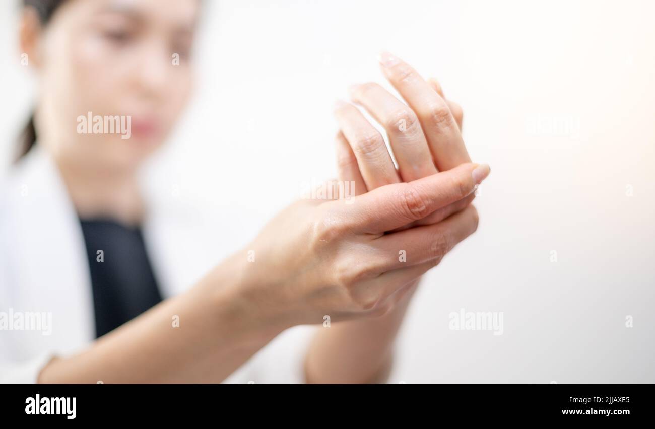 Donna asiatica che tiene la sua mano dolorosa sul polso primo piano. Difficoltà nell'utilizzo del computer. Sindrome da ufficio dolore alla mano lavorando davanti al laptop. Foto Stock