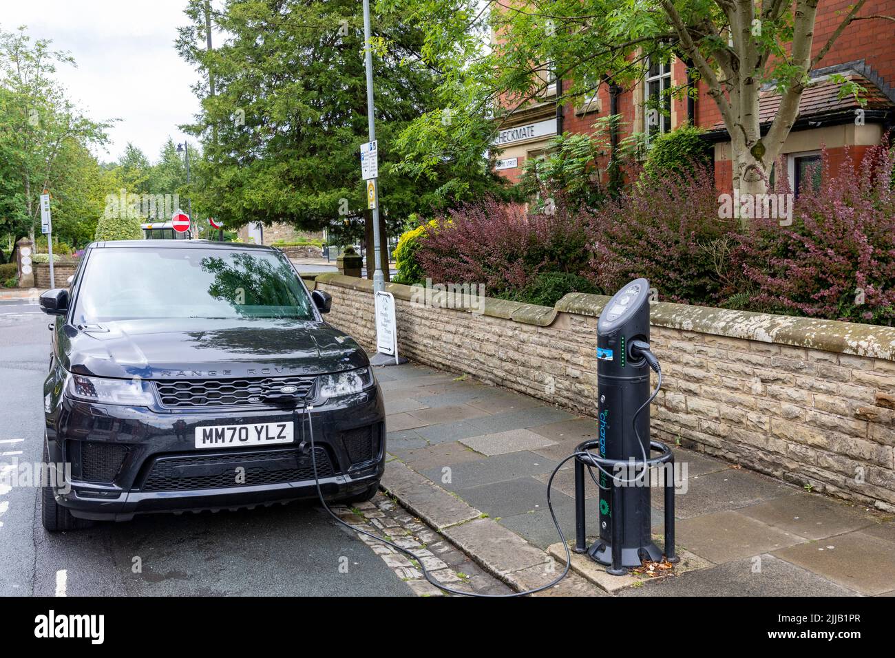Il modello ibrido Black Range Rover Sport viene caricato tramite un caricatore per auto elettriche a Whalley, vicino a Clitheroe, Lancashire, Regno Unito Foto Stock