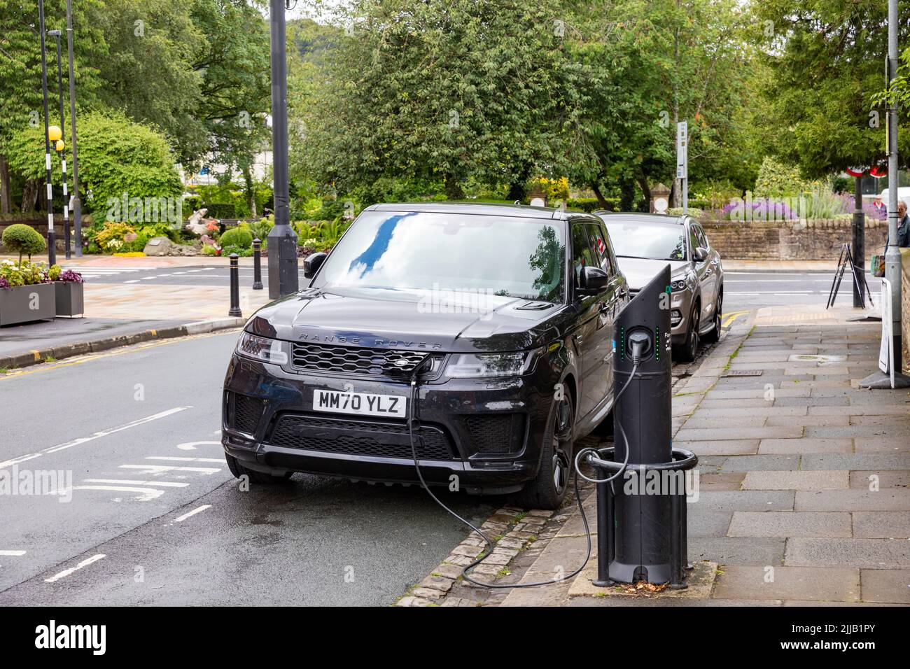Il modello ibrido Black Range Rover Sport viene caricato tramite un caricatore per auto elettriche a Whalley, vicino a Clitheroe, Lancashire, Regno Unito Foto Stock