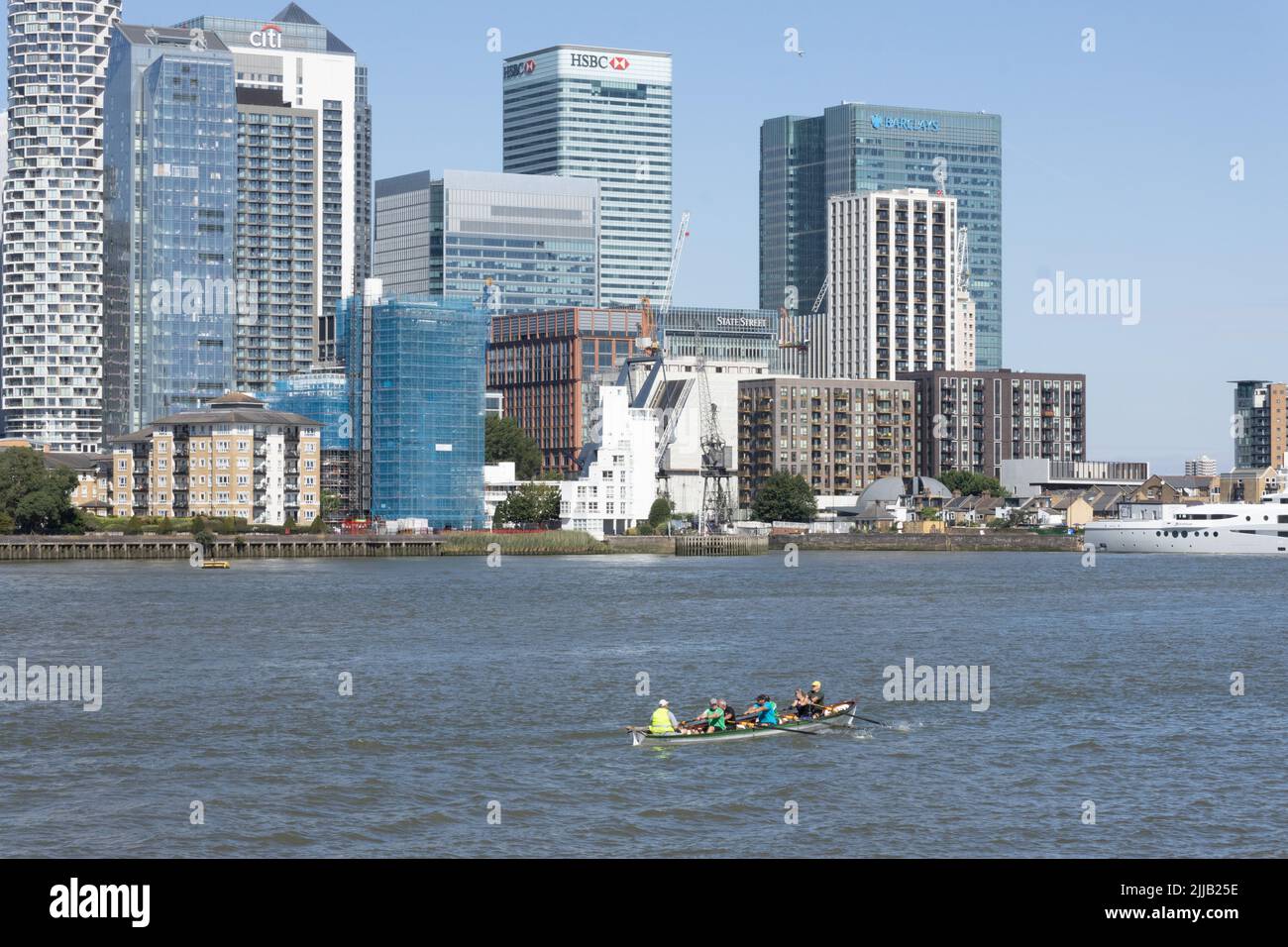 Vogatori in dingy con superyacht Stardust off Canary Wharf, City of London, UK Foto Stock