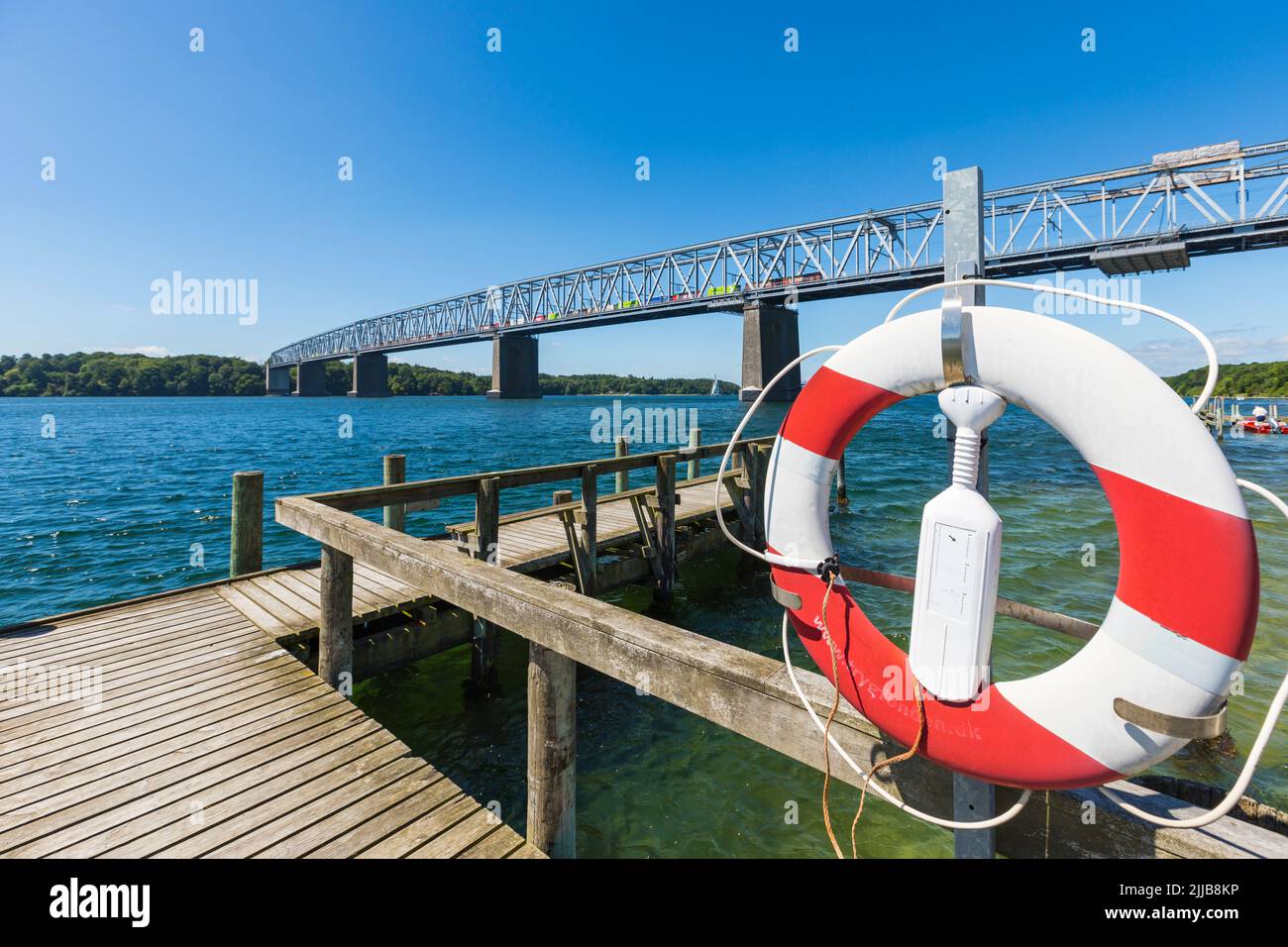 Vecchio ponte ferroviario e stradale combinato che attraversa la piccola cintura a Middelfart, Danimarca. Vista dal molo di Snoghøj, boa di vita in primo piano. Foto Stock