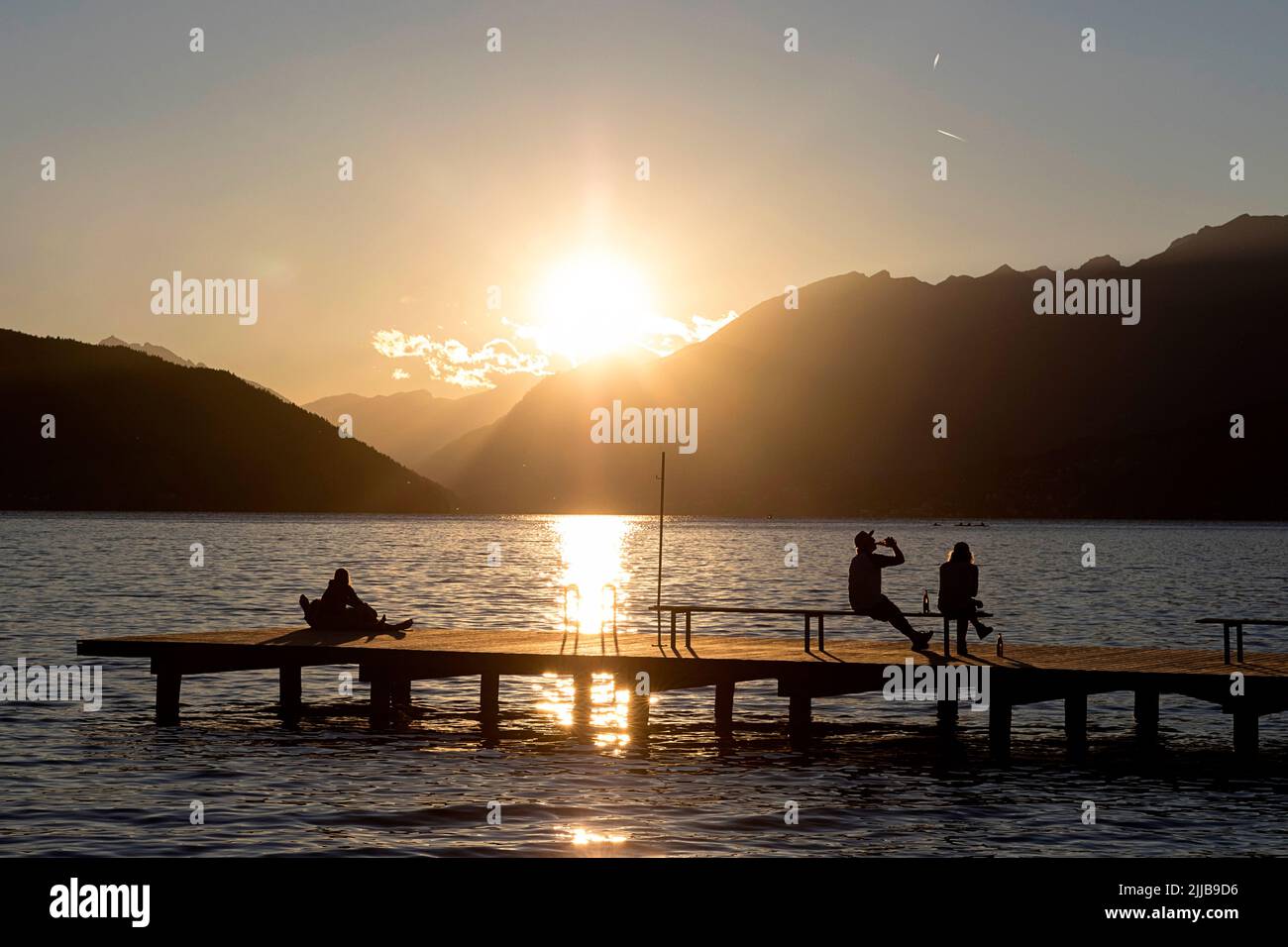 Gli abitanti del luogo si godono alla fine di una bella giornata estiva su un molo di legno a Millstätter vedere il lago in Carinzia, Austria Foto Stock
