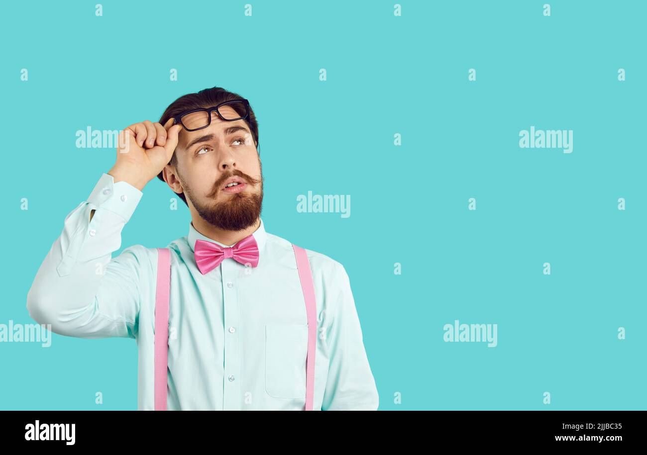 L'uomo caucasico bearded guarda in su, alzando gli occhiali dagli occhi vestiti in camicia bianca Foto Stock