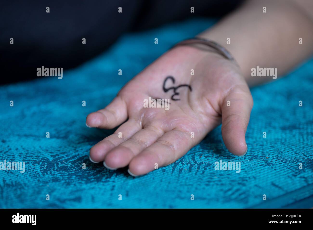 Primo piano della mano femminile con il simbolo Om dipinto sul tappeto yoga. Concetto di yoga background. Foto Stock