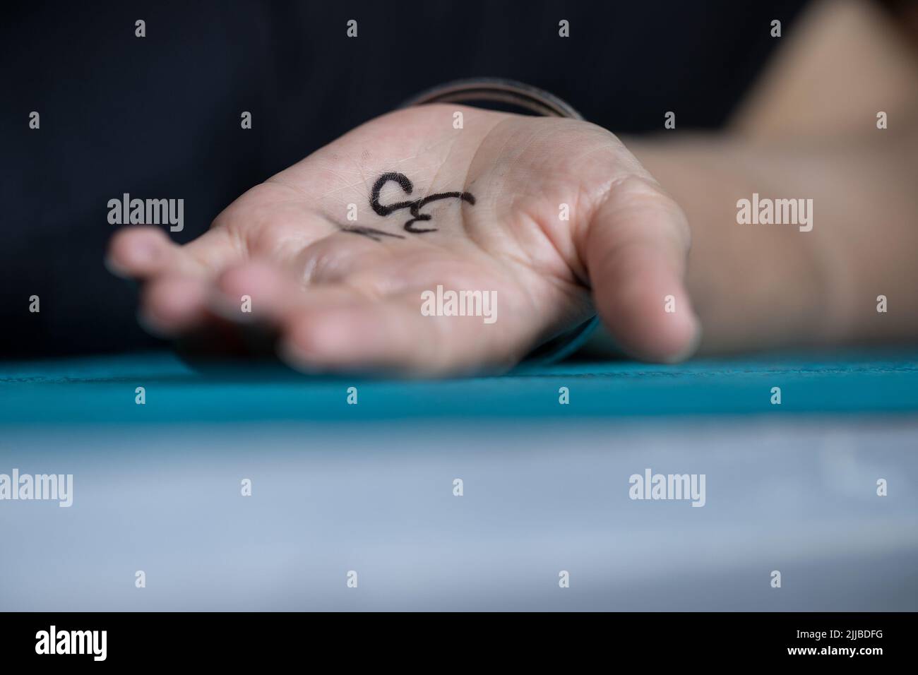 Primo piano della mano femminile con il simbolo Om dipinto sul tappeto yoga. Concetto di yoga background. Foto Stock