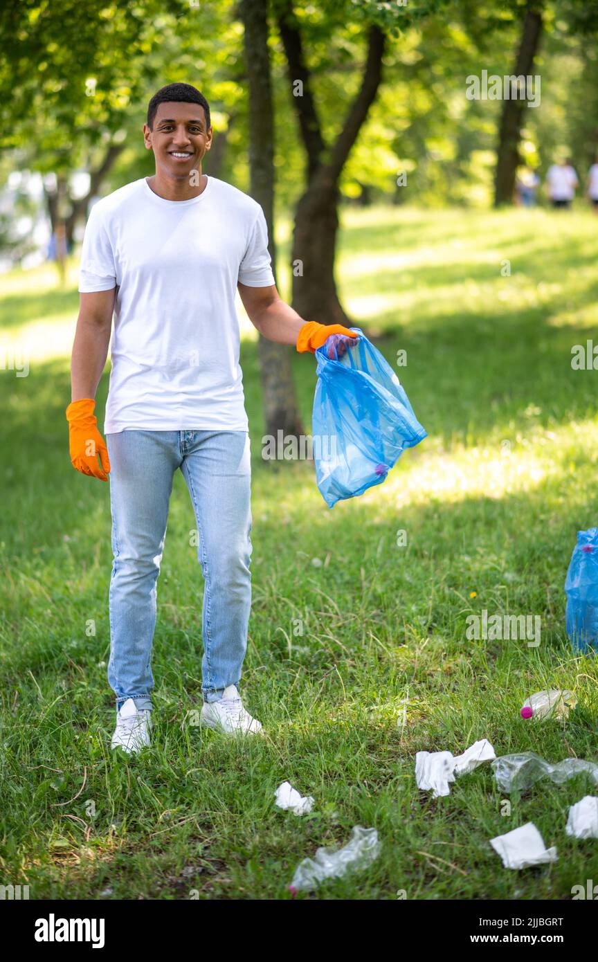 Uomo con sacco in piedi sorridente alla macchina fotografica Foto Stock