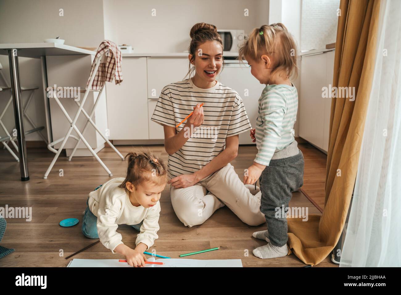 Genitore femminile che si prende cura di aiutare i suoi figli a disegnare Foto Stock