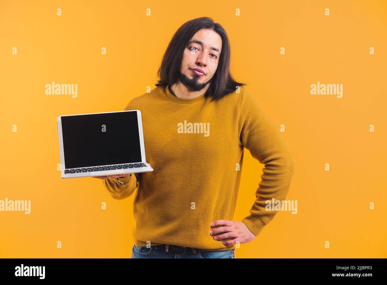 Una persona dai capelli lunghi con una barba in una stanza che fa pubblicità ad un taccuino e che guarda nella lente all'interno di una stanza su uno sfondo arancione. Foto di alta qualità Foto Stock