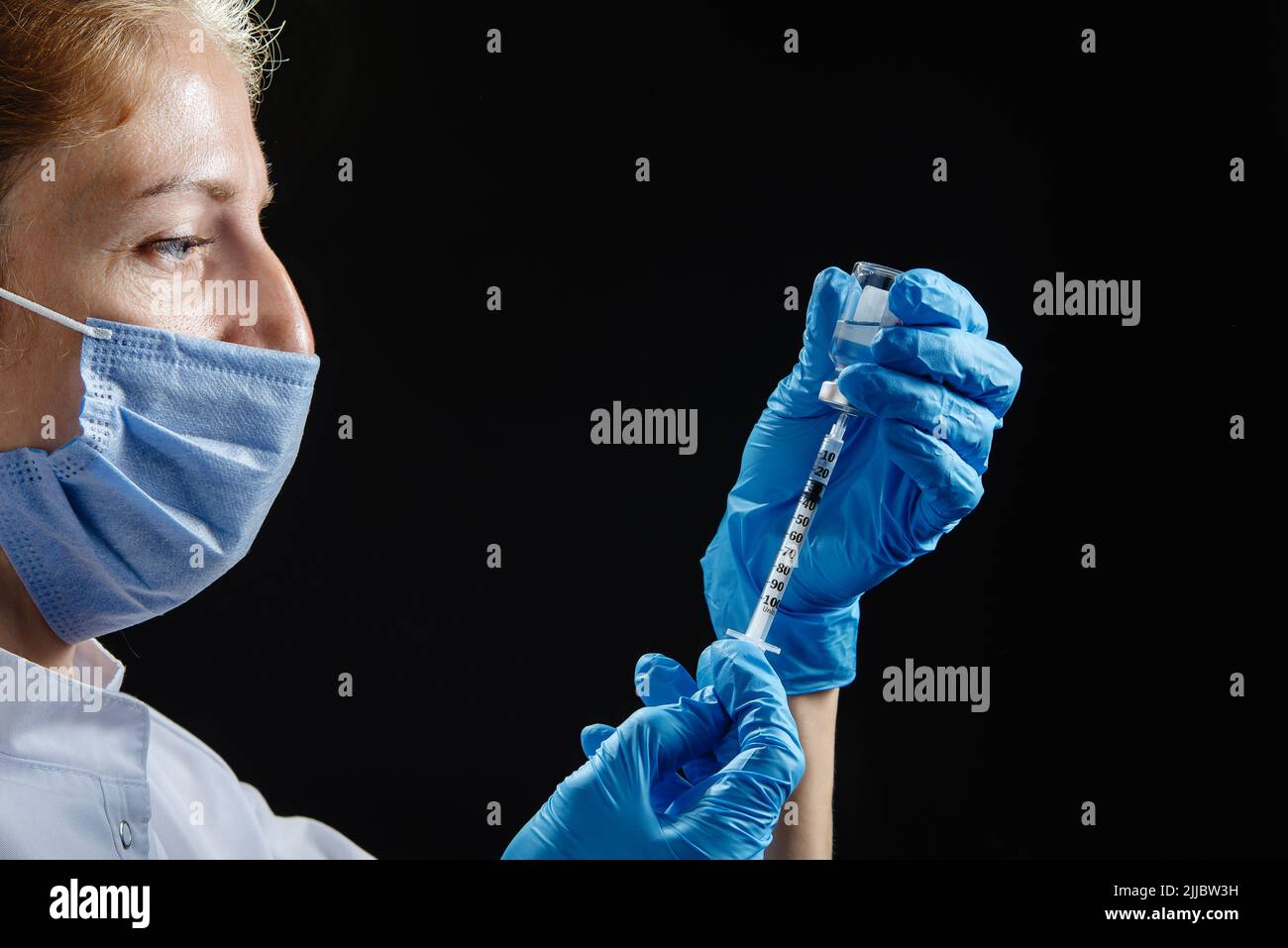 Il medico si prepara a fare l'iniezione. Un'infermiera femminile riempie la siringa con il medicinale. Foto Stock