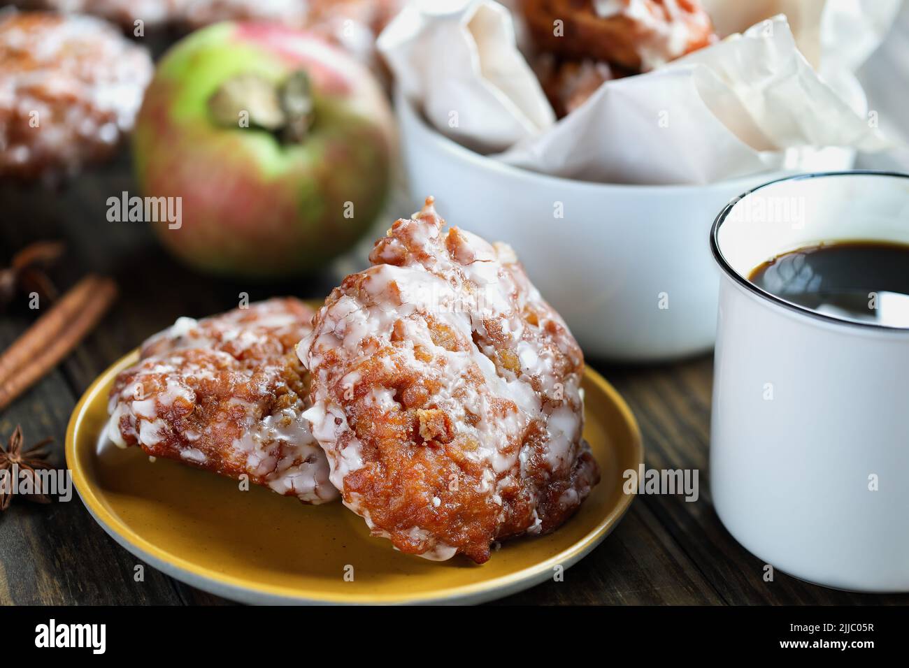 Frittelle di mele glassate e caffè caldo con mele fresche, corteccia di cannella e anice. Messa a fuoco selettiva con sfondo sfocato. Foto Stock