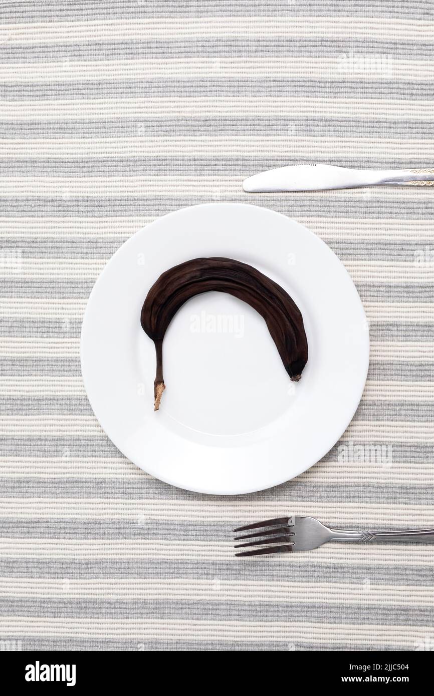 Banana al forno essiccata al sole su piatto bianco. Cibo Thai conservato, snack sano. Superfood, vegan, vegetariano concetto di cibo. Foto Stock