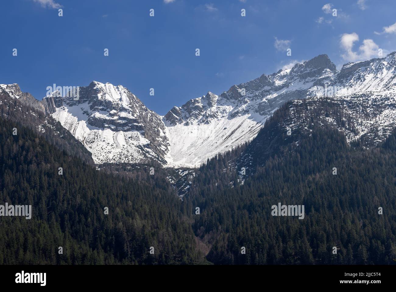 Nevi eterne sulle cime delle Dolomiti ricoperte di fitte foreste secolari proprio lungo il pendio Foto Stock