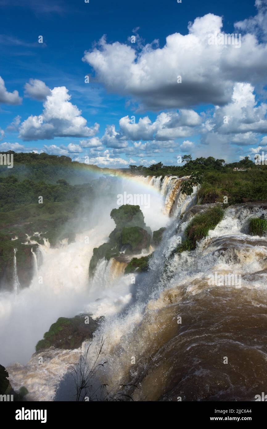 Enorme bella vista panoramica dalla caduta di Iguazu, Catarata argentina lato blu cielo verde foresta torbida acque del fiume Iguazu forte corrente. Foto Stock