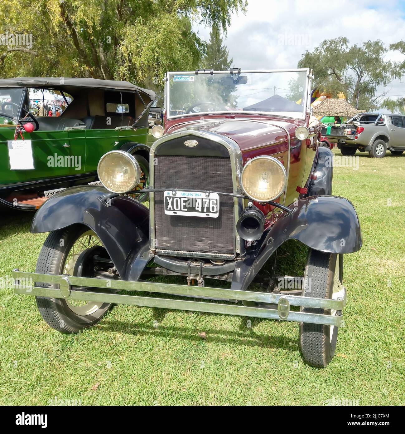 Vecchio maroon rosso Ford modello B 1932 quattro porte convertibile in campagna. Vista frontale. Natura verde erba e alberi. Mostra di auto classiche. CopySpace Foto Stock