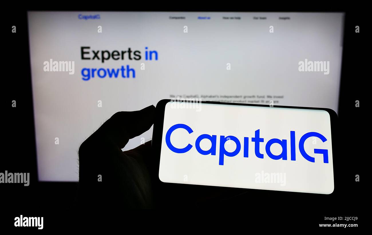 Persona che detiene il telefono cellulare con il logo dell'investitore americano CapitalG Management Company LLC sullo schermo di fronte alla pagina web. Mettere a fuoco sul display del telefono. Foto Stock