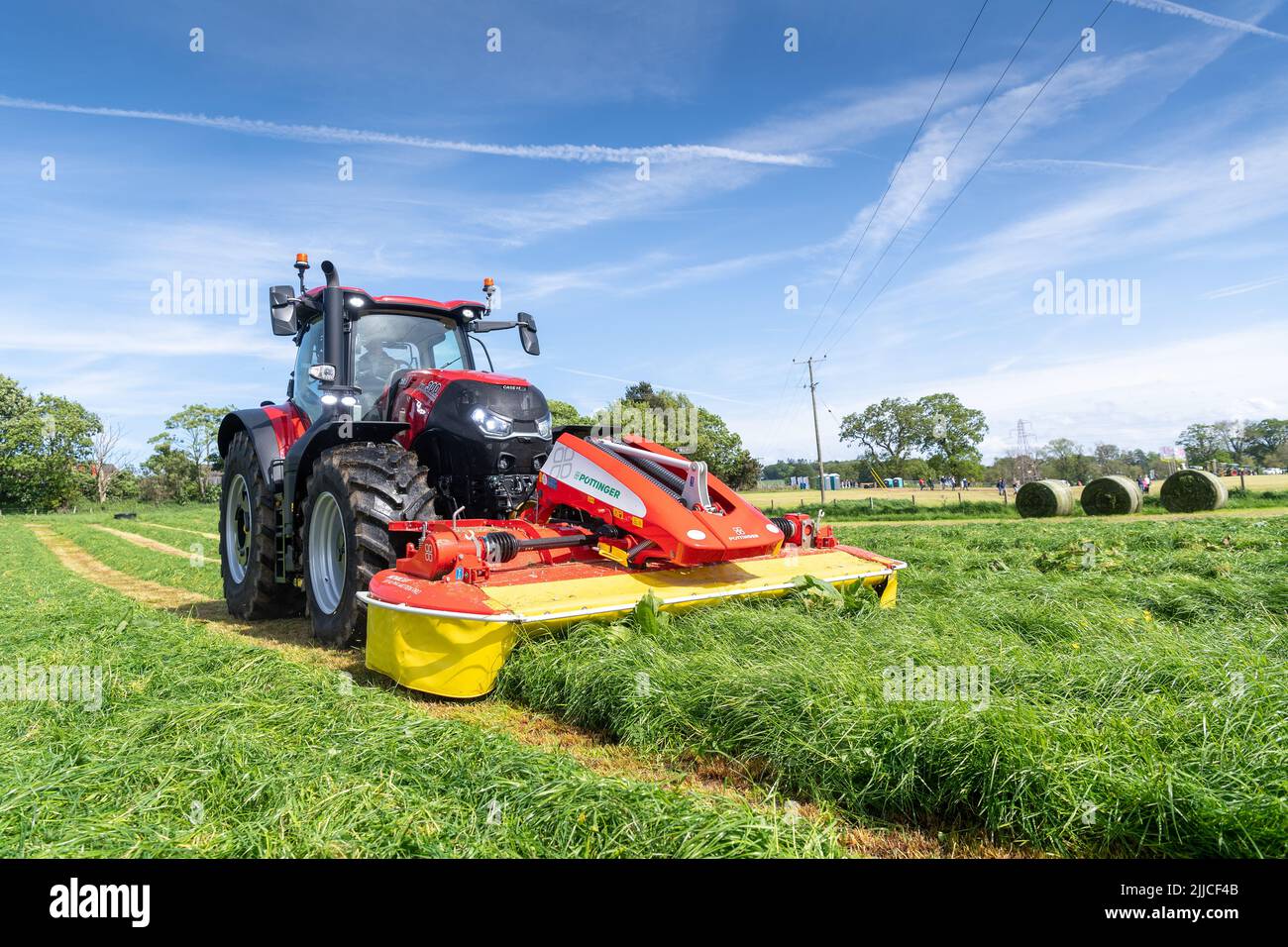 Coltivatore che rasa un campo di erba con un Case 300 e una falciatrice Pottinger montata anteriormente. Dumfries, Scozia, Regno Unito. Foto Stock