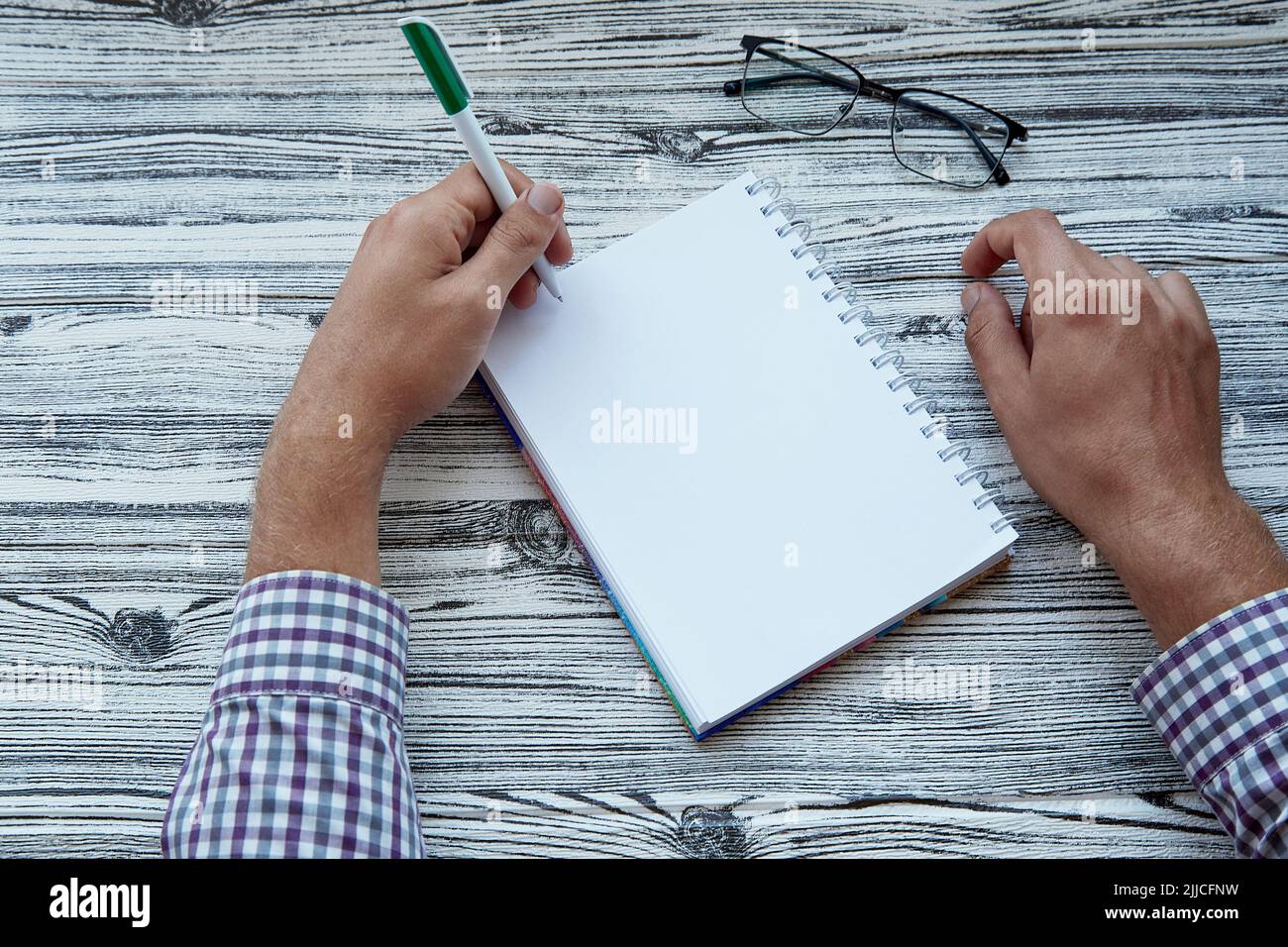 L'uomo che scrive nel blocco note mock in su, usando la sua mano sinistra. Foto concettuale del giorno di sinistra. Spazio di copia Foto Stock