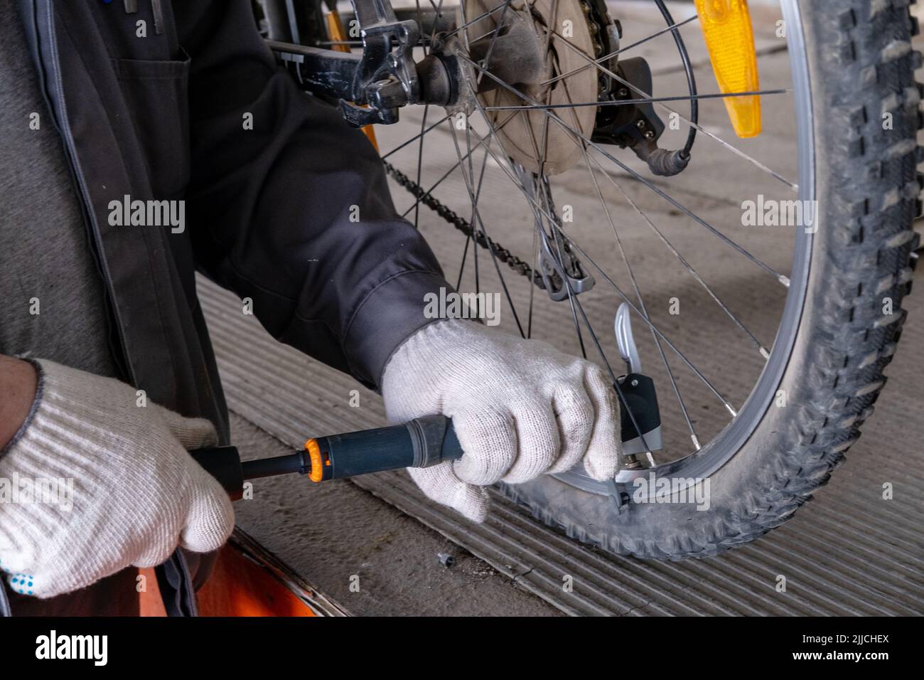 Primo piano di un uomo che pompa la ruota della bicicletta sulla strada. Riparazione di biciclette, ciclista sono pneumatici pompanti. L'uomo gonfia la ruota della bicicletta utilizzando una pompa. Pompaggio dell'aria Foto Stock