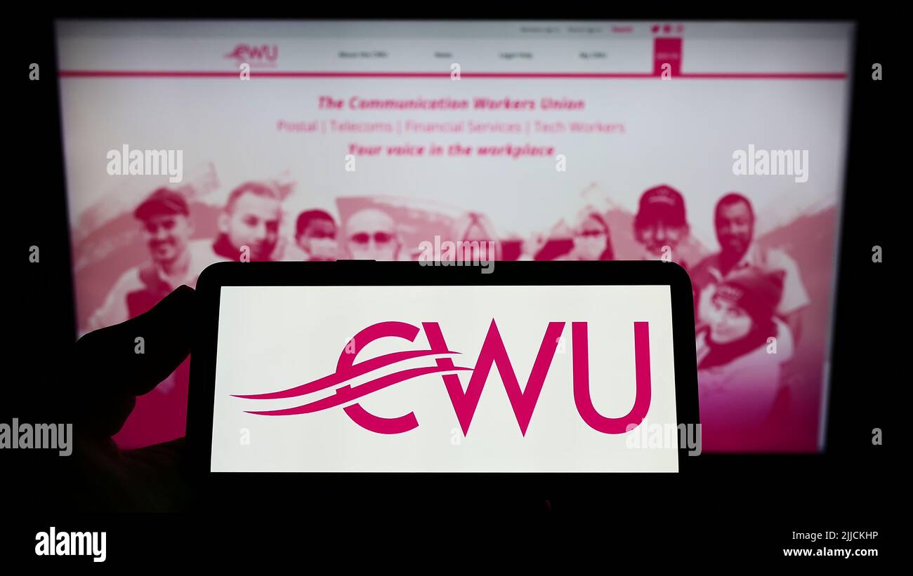 Persona che tiene uno smartphone con il logo della British Communication Workers Union (CWU) sullo schermo di fronte al sito Web. Mettere a fuoco sul display del telefono. Foto Stock