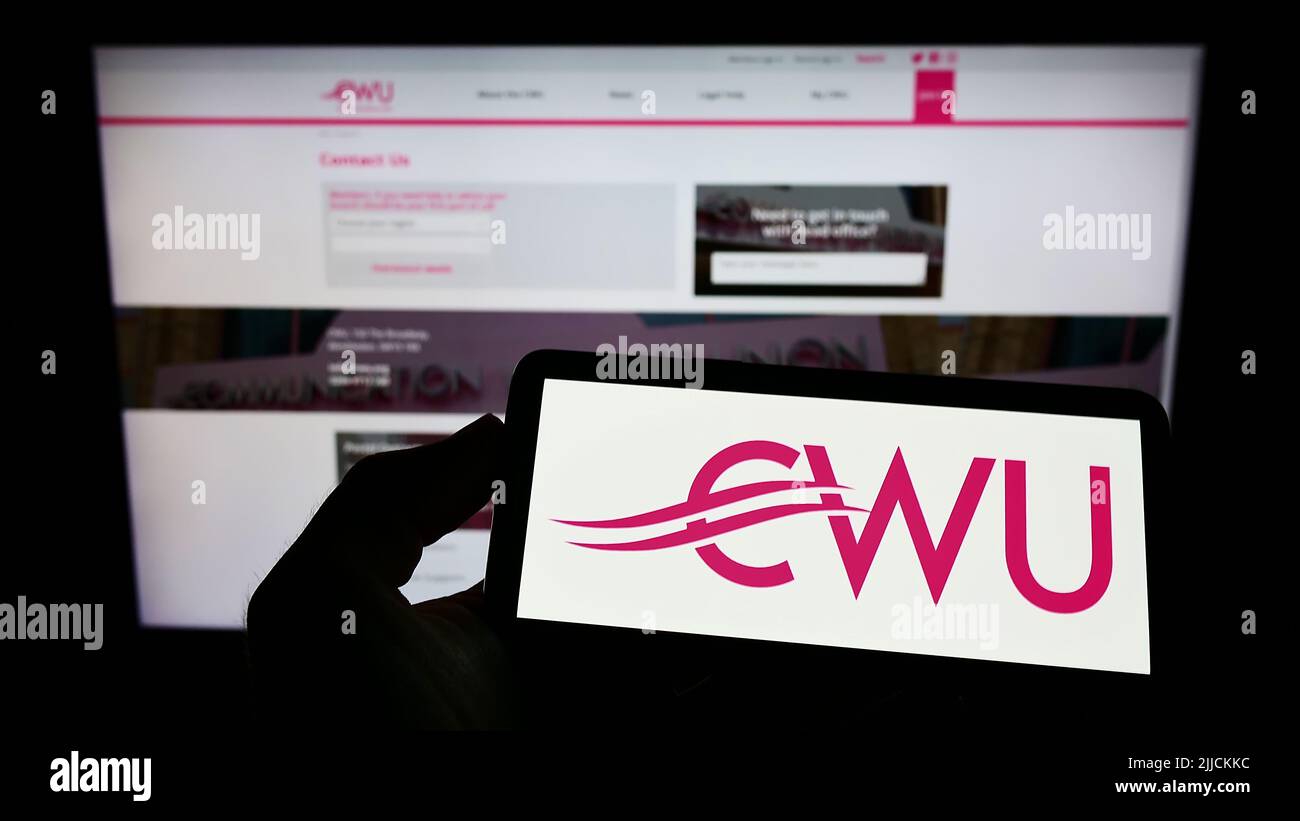 Persona che tiene il cellulare con il logo della British Communication Workers Union (CWU) sullo schermo di fronte alla pagina web. Mettere a fuoco sul display del telefono. Foto Stock