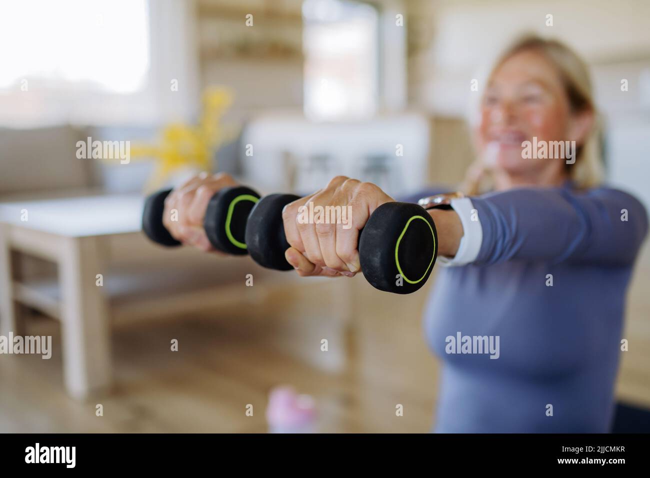 Misura la donna anziana che si esercita con i dumbbells a casa, concetto di stile di vita attivo. Foto Stock