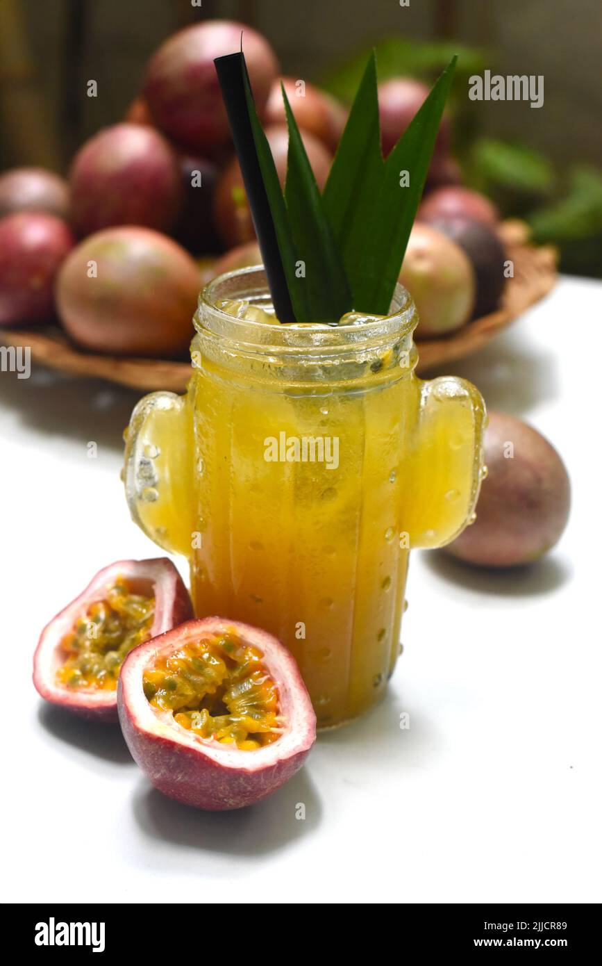 Tè alla frutta della passione su un tavolo bianco con mucchio di frutti della passione Foto Stock
