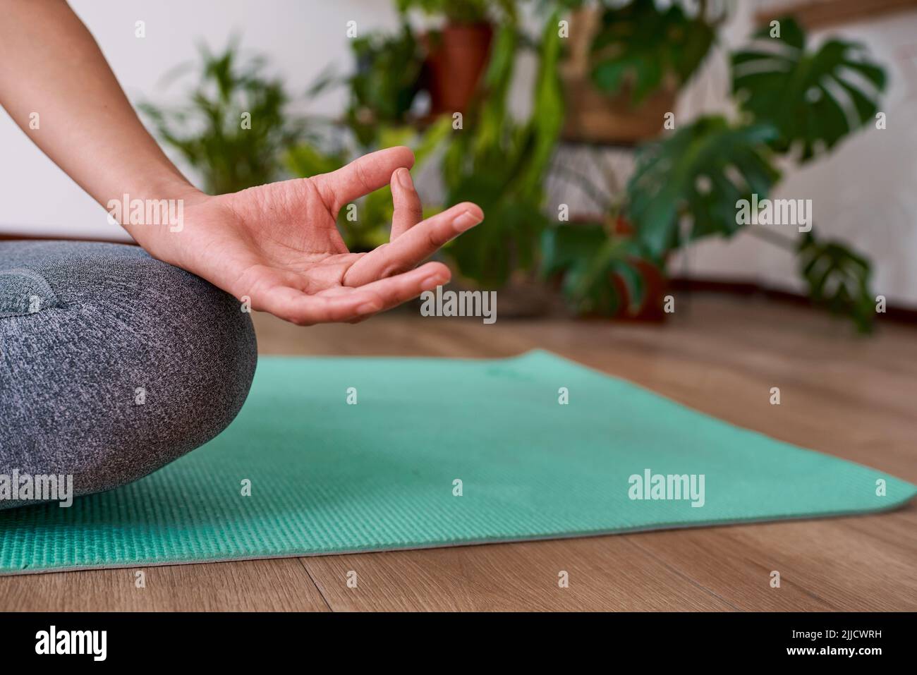Un primo piano di donna seduta sul tappeto yoga con le mani in Gyan mudra, dita toccare Foto Stock