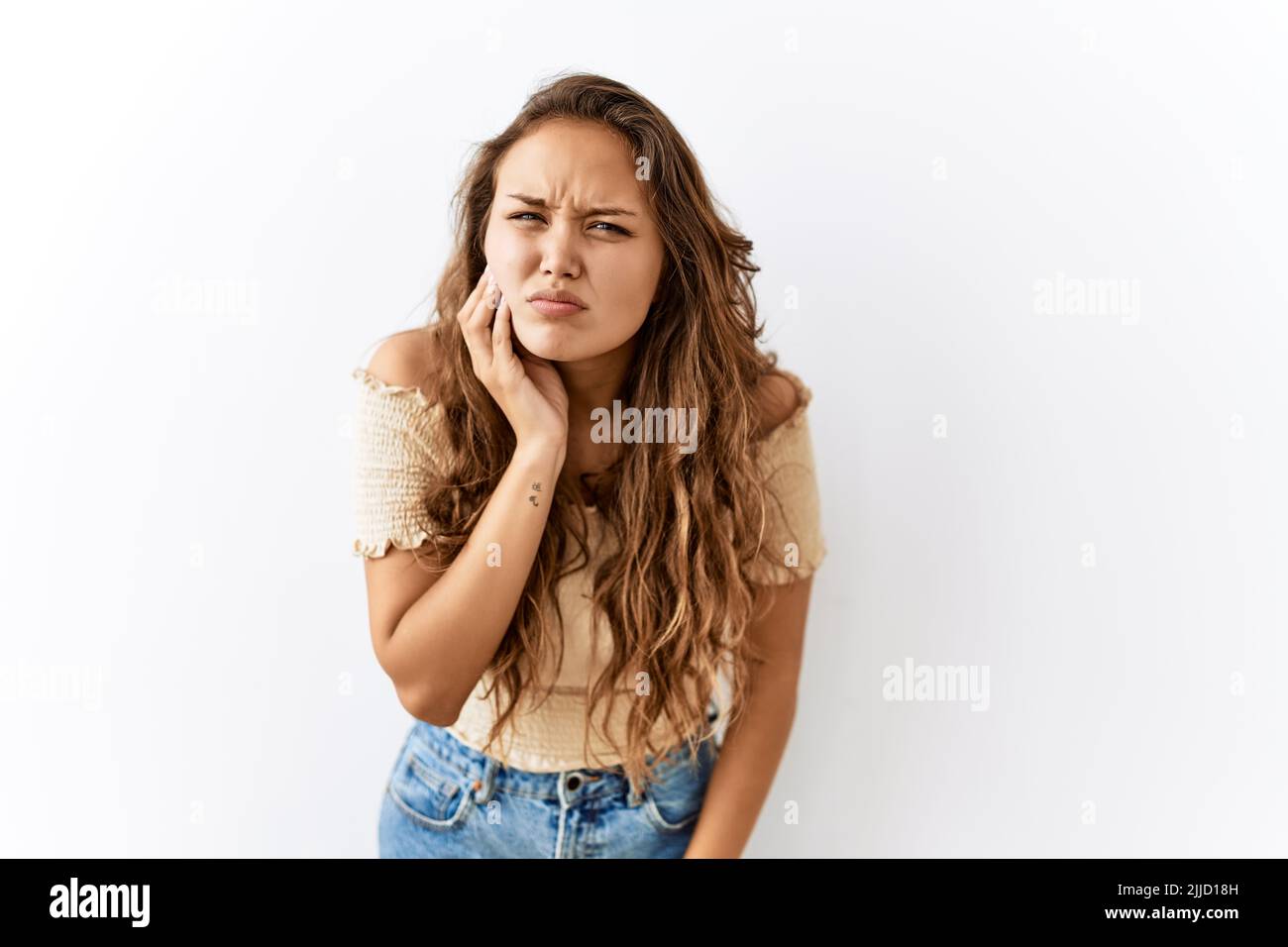Bella donna ispanica in piedi su isolato mentre sfondo toccando la bocca con mano con espressione dolorosa a causa di mal di denti o illne dentale Foto Stock