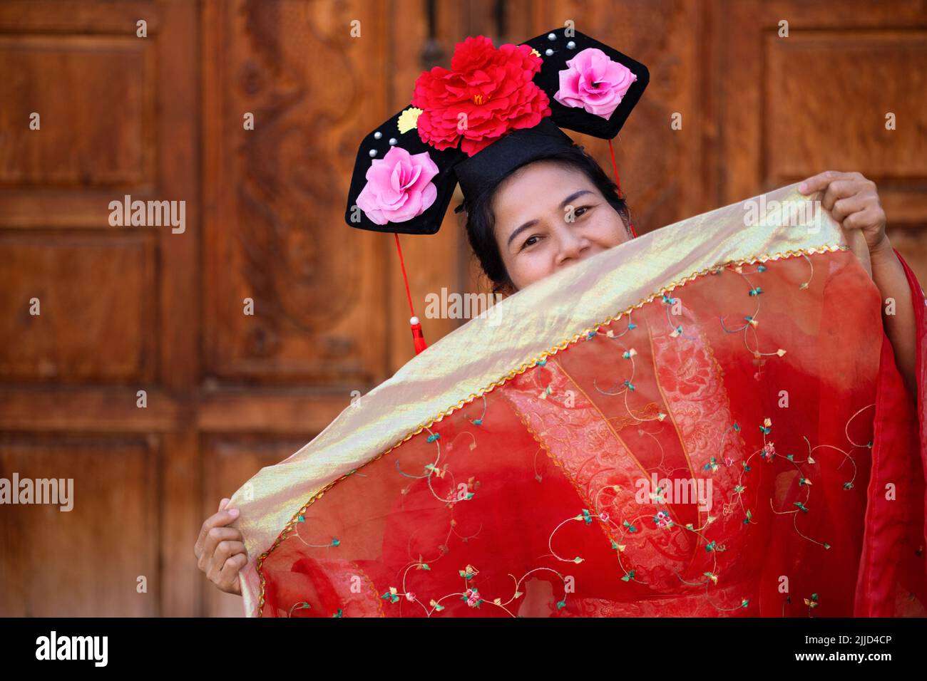 Gioiosa donna cinese in posa con abito tradizionale e acconciatura Foto Stock